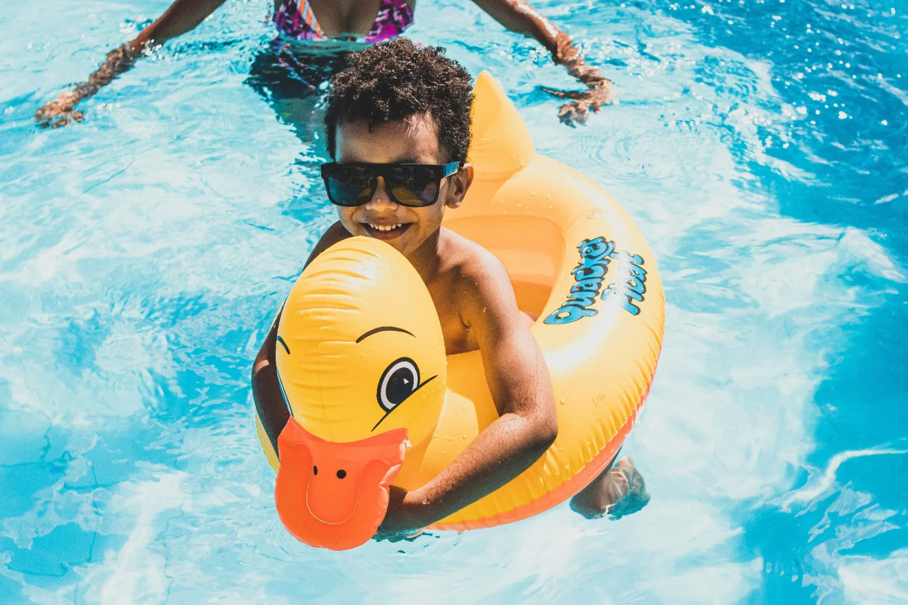 Happy child on a duck float enjoying a financed backyard swimming pool in Utah