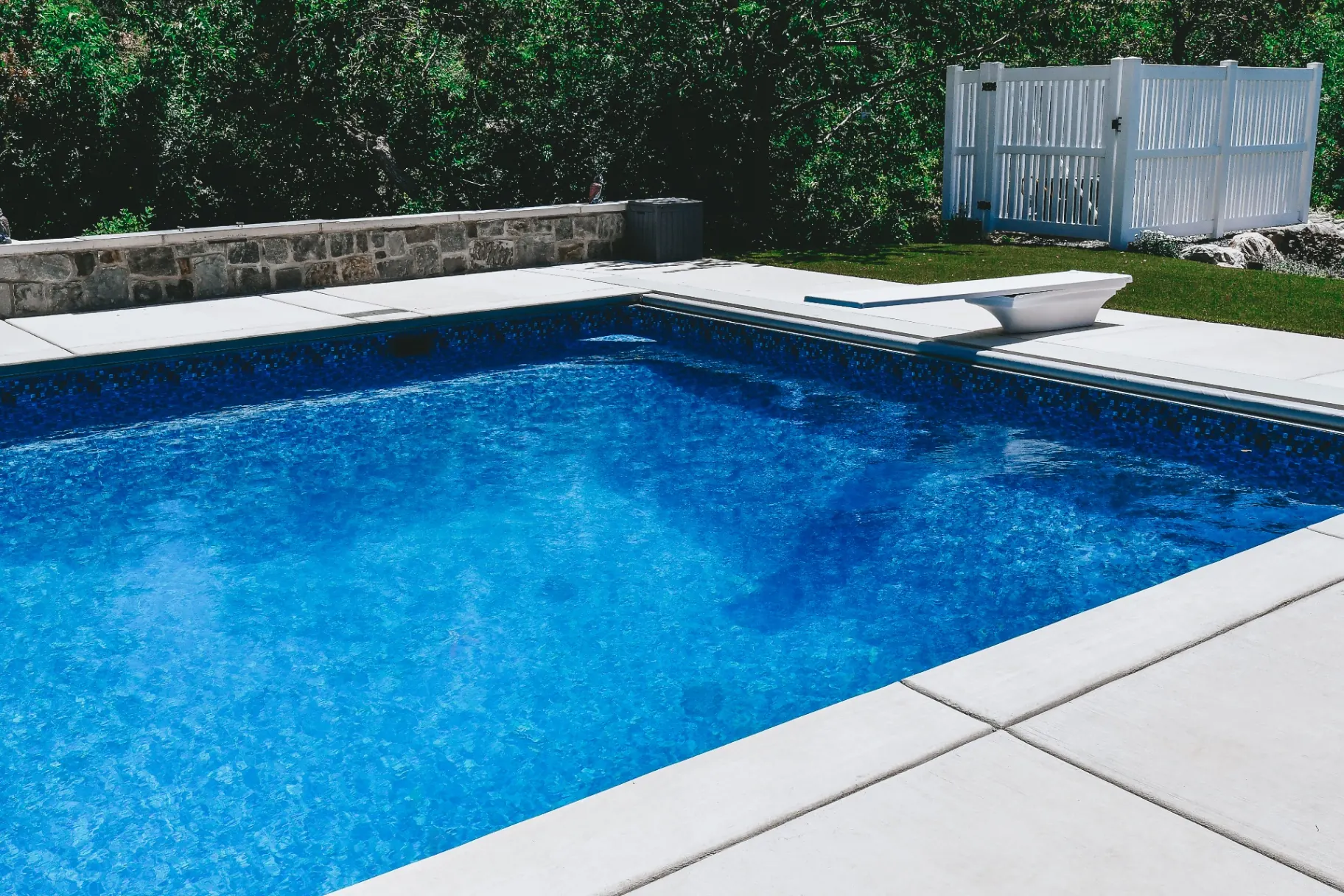 Kaysville Utah Vinyl Pool with Diving Board - Barr Pool Builders Blue mosaic-tile vinyl liner swimming pool with diving board and concrete deck in Kaysville, Utah by Barr Pool Builders