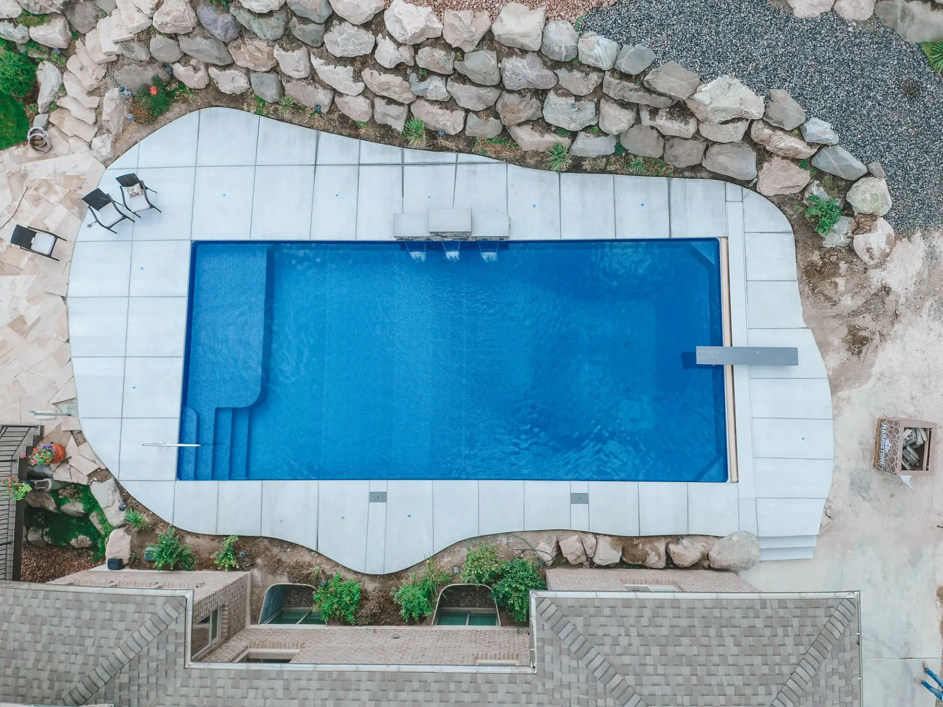 Ogden Utah Aerial Rectangle Vinyl Pool with Tanning Ledge - Barr Pool Builders Aerial drone view of a modern rectangle vinyl inground swimming pool with tanning ledge, diving board and freeform stone patio in Ogden, Utah by Barr Pool Builders