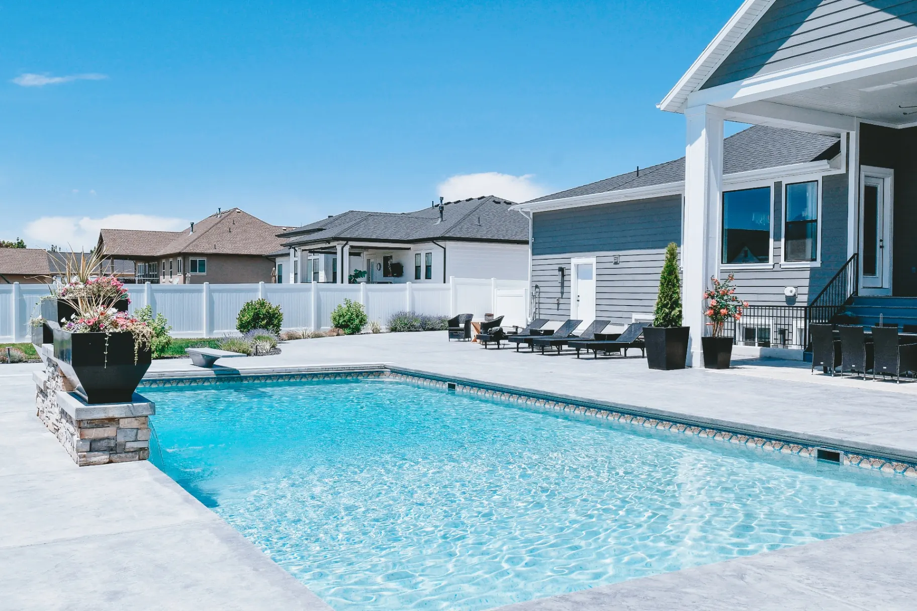Custom vinyl inground swimming pool with stamped concrete patio, diving board and outdoor dining in Farmington, Utah by Barr Pool Builders
